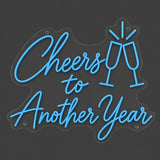 Blue Cheers to Another Year neon sign lit on a dark gray background