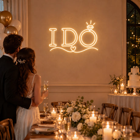 Couple at a wedding reception in front of an I Do neon sign