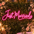 Pink Just Married neon sign on a flower wall wedding backdrop