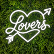 White Lovers neon sign with heart and arrow on a green wall