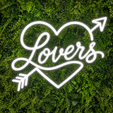 White Lovers neon sign with heart and arrow on a green wall