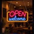 Open welcome neon sign glowing in a cafe entrance window