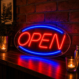 Oval open neon sign shown lit at night above a shop entrance