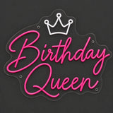Pink Birthday Queen crown neon sign lit on a dark gray background