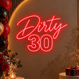 Red Dirty 30 neon sign on a birthday party backdrop