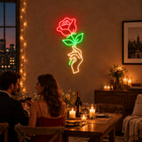 Hand holding rose neon sign at a romantic dinner